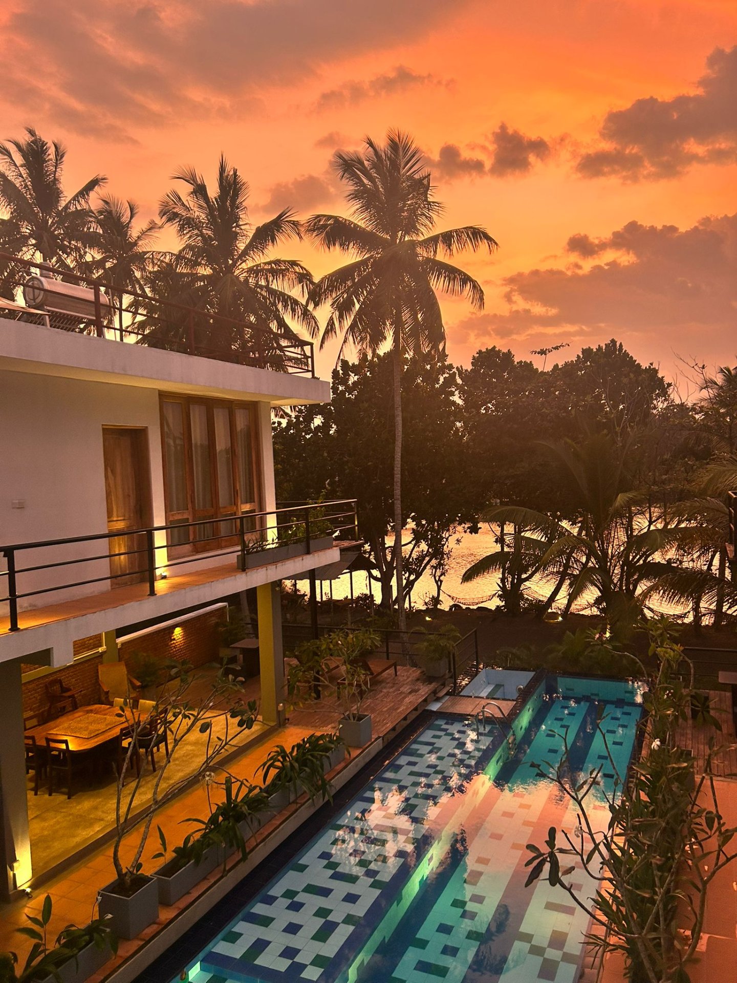 Tropical Sunset by Ko Lake Villa with Pool - Ko Lake Villa boutique lakefront accommodation on Koggala Lake Sri Lanka: Enjoy a stunning tropical sunset view by a modern villa featuring a private pool and lush palm trees. Afteredark poolside cocktails and night fishermen