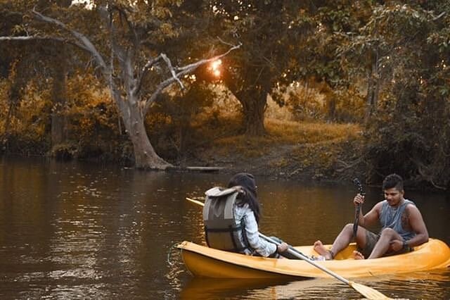 Lake kayaking at sunset, surrounded by lush trees, while staying at Ko Lake Villa, Sri Lanka.