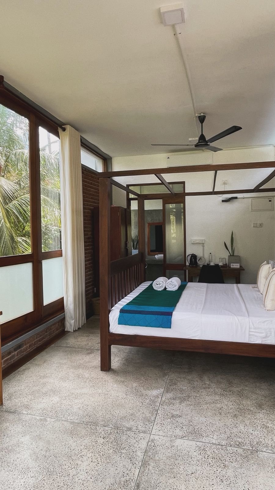 Spacious bedroom at Ko Lake Villa with a four-poster bed, large windows showing lush greenery outside, and a modern tropical design.