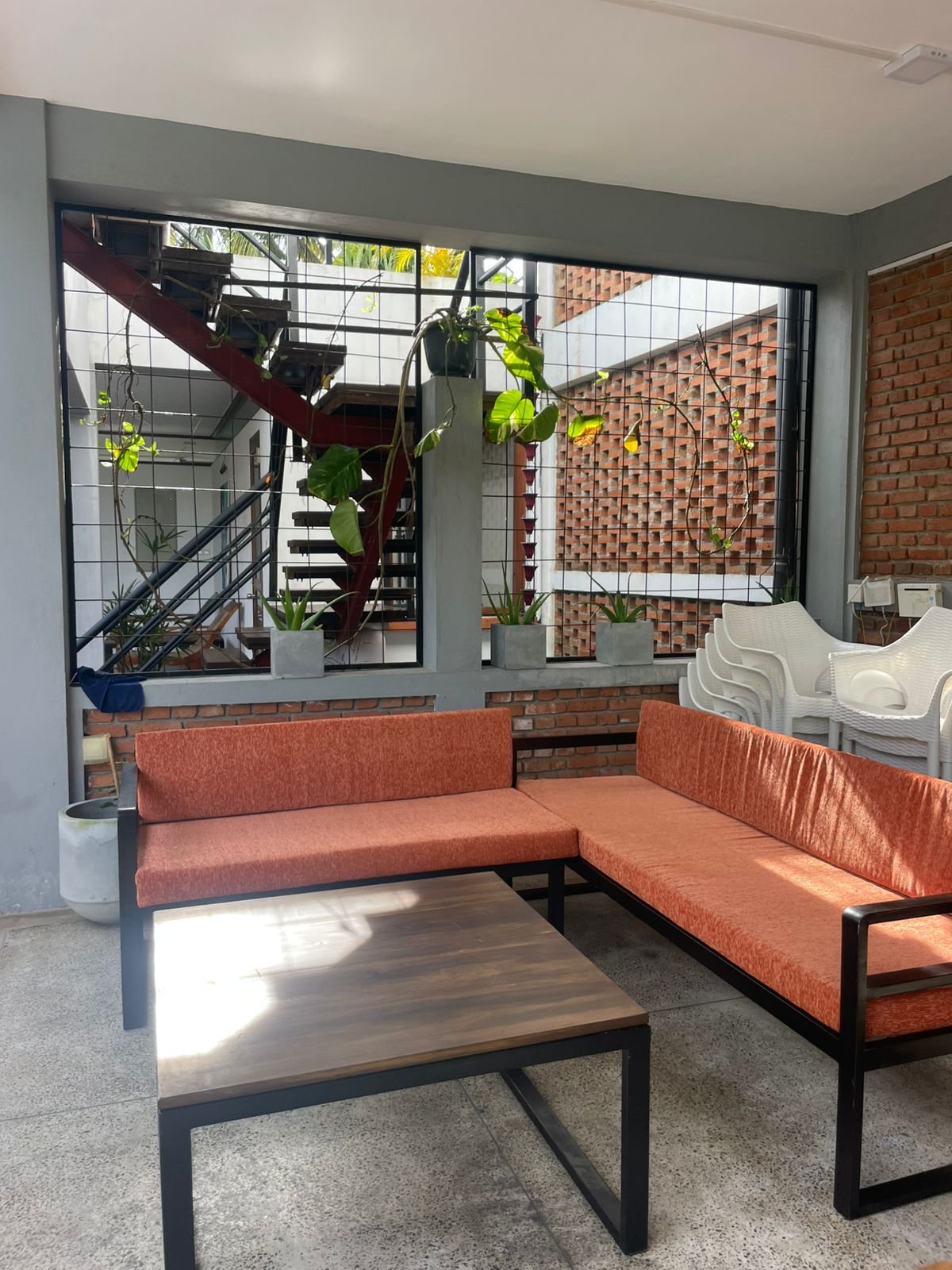 Pool side lounger to relax or snooze under fa - Ko Lake Villa boutique lakefront accommodation on Koggala Lake Sri Lanka: Relaxing contemporary lounge area with orange L-shaped sofa, wooden coffee table, exposed brick, and lush indoor plants.